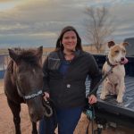 female standing next to a horse and a medium sized dog